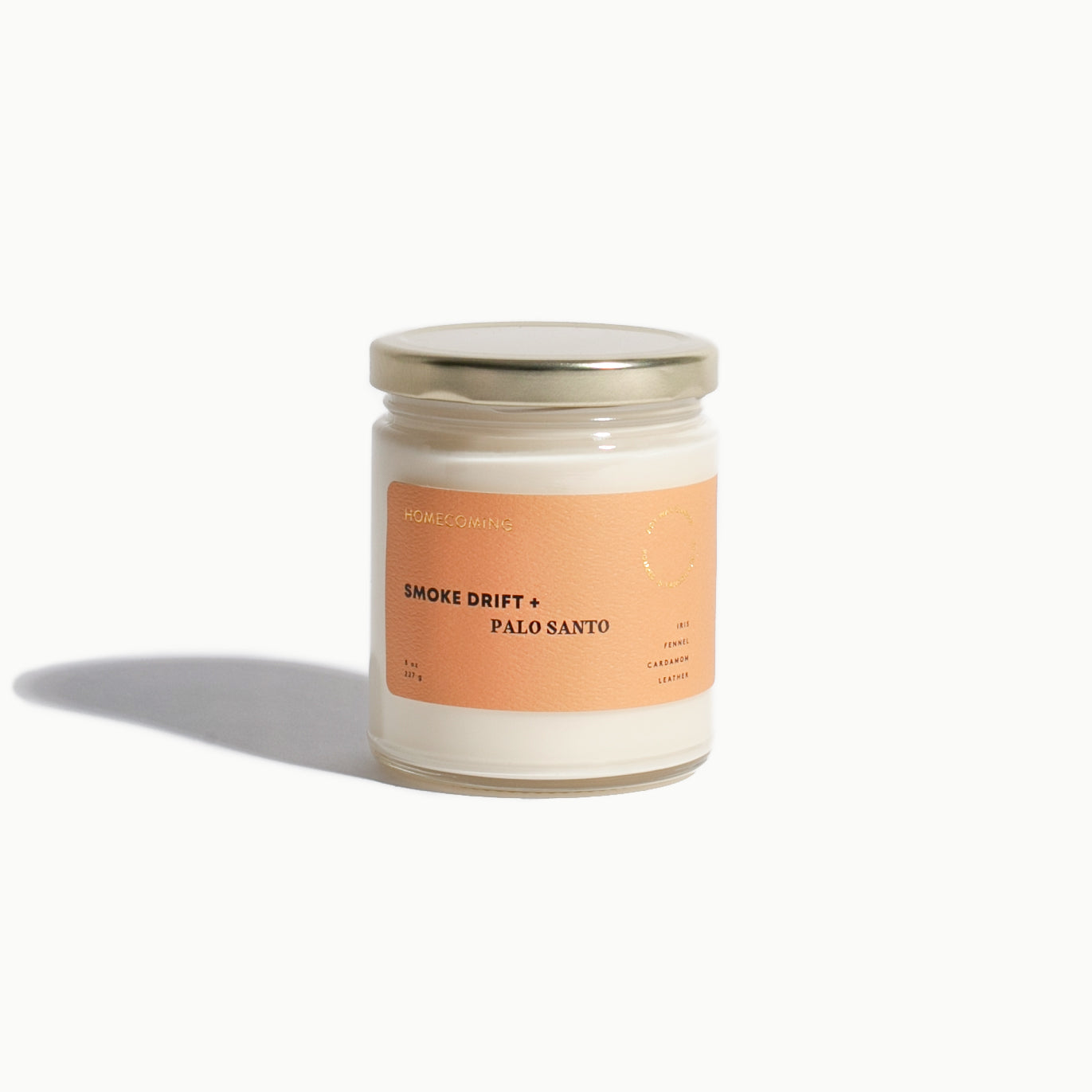 Candle jar with a peach-colored label on a white background